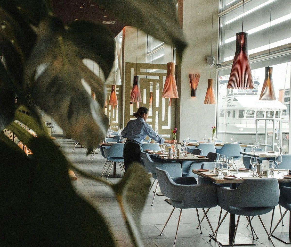 Service-Mitarbeiterin deckt in einem hellen Restaurant einen Tisch ein